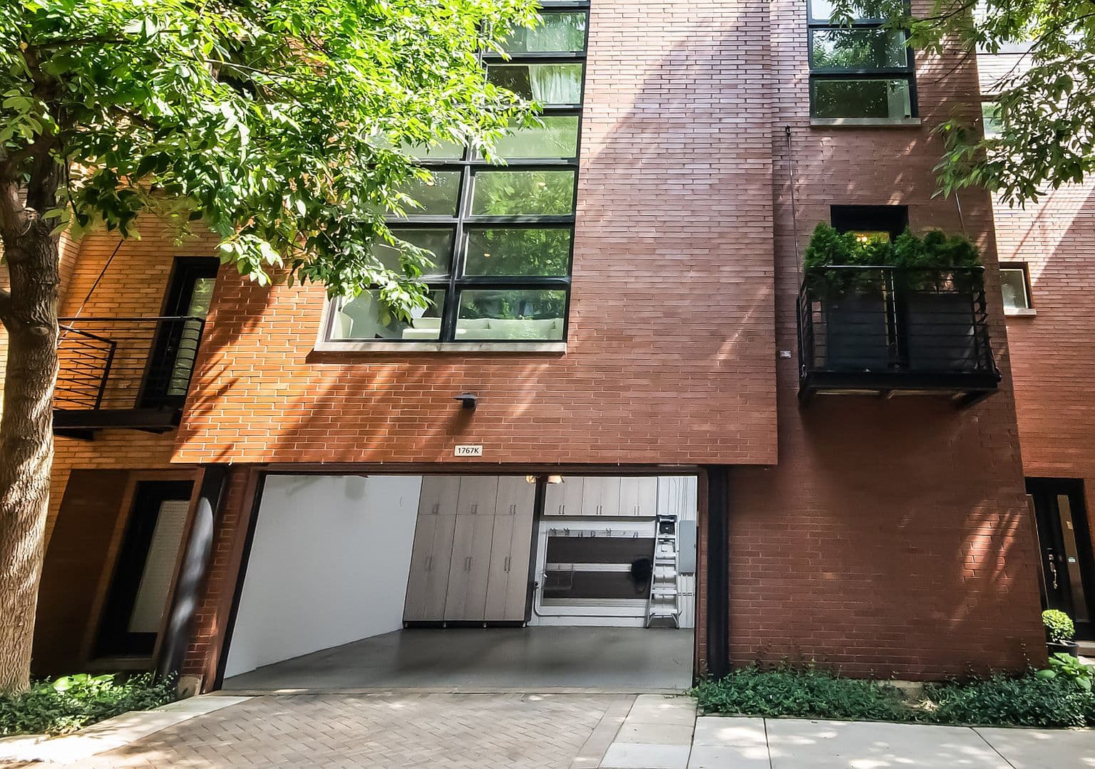 Modern brick façade with balcony and oversized windows.
