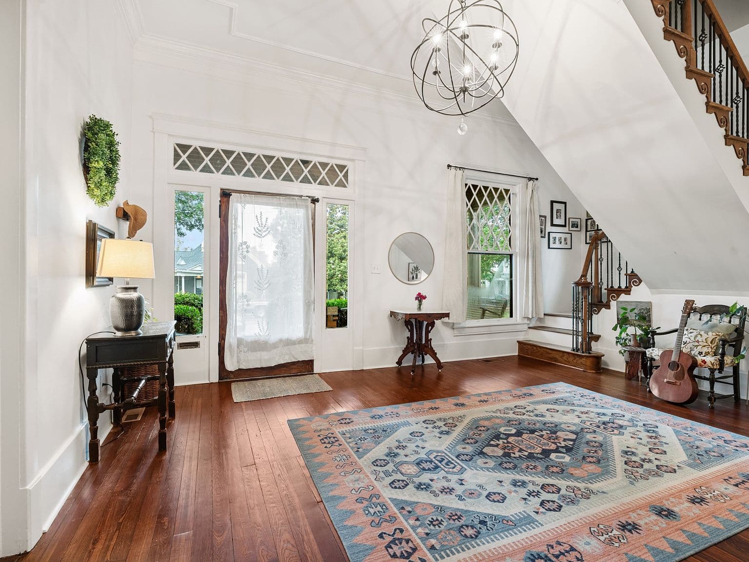 Elegant staircase and airy living space with rich hardwood.