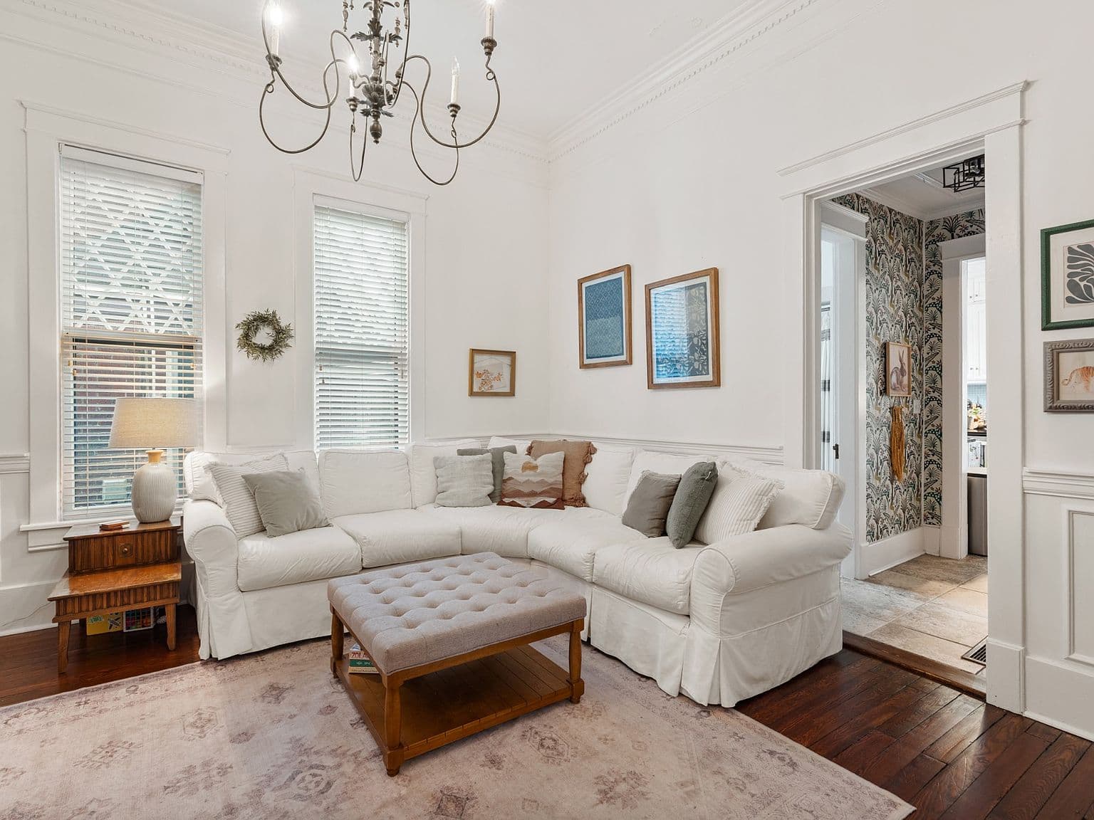 Cozy living room with tall windows and elegant chandelier.