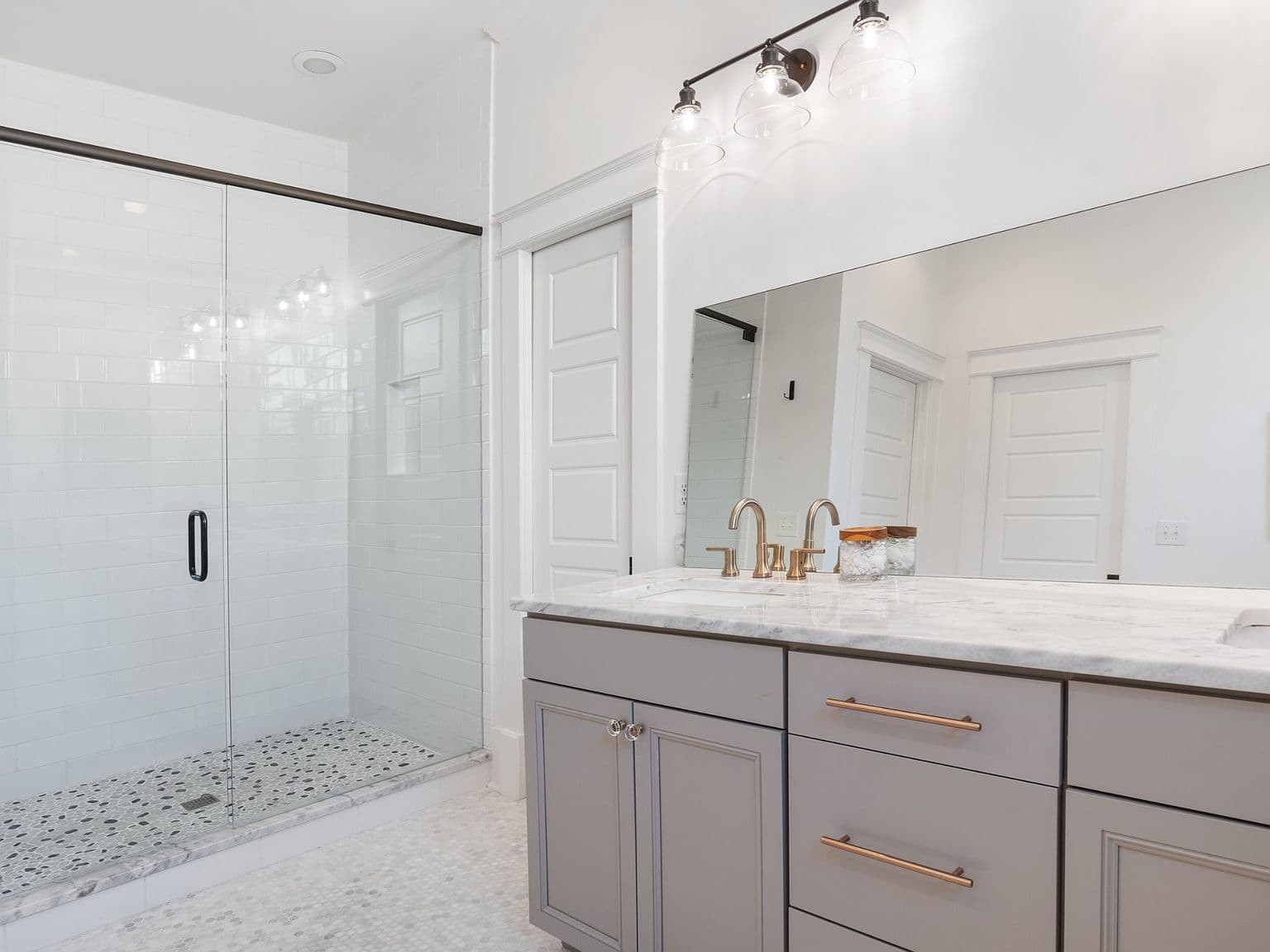 Sleek glass shower, marble counters, and oversized mirror.