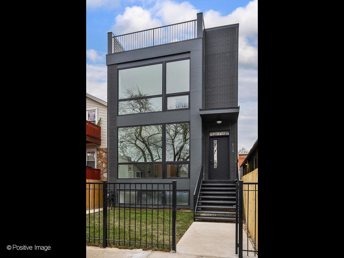 Striking contemporary facade with expansive glass and rooftop rail
