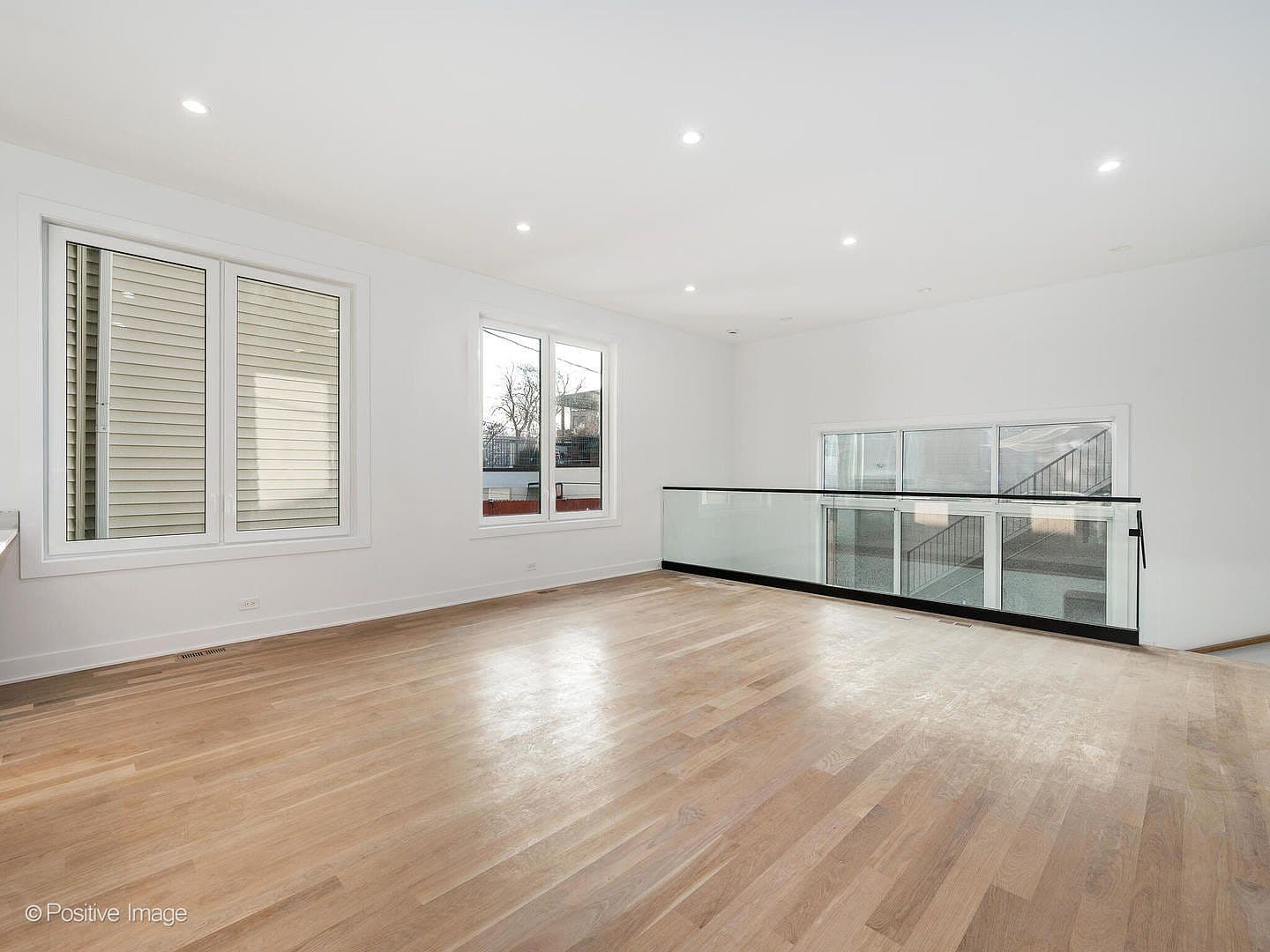 Light-filled rear family room with glass stairwell railing