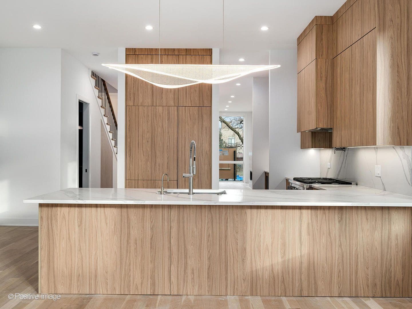 Oversized walnut island with sculptural pendant lighting