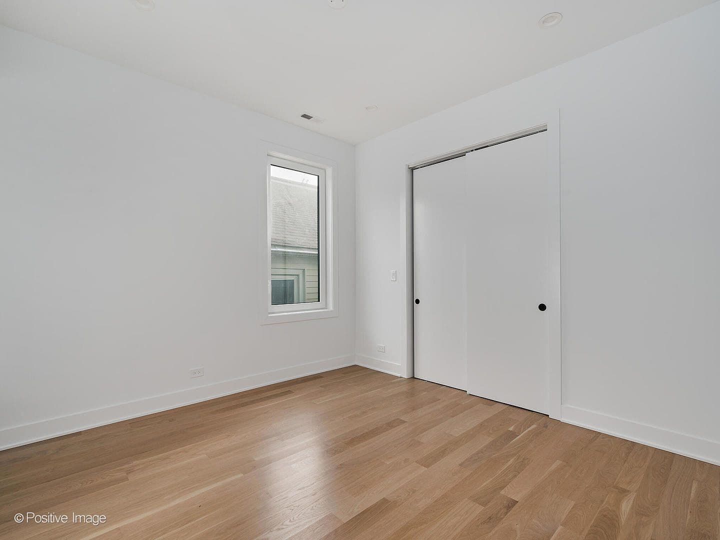 Bright bedroom with sliding-door closet and oak floors