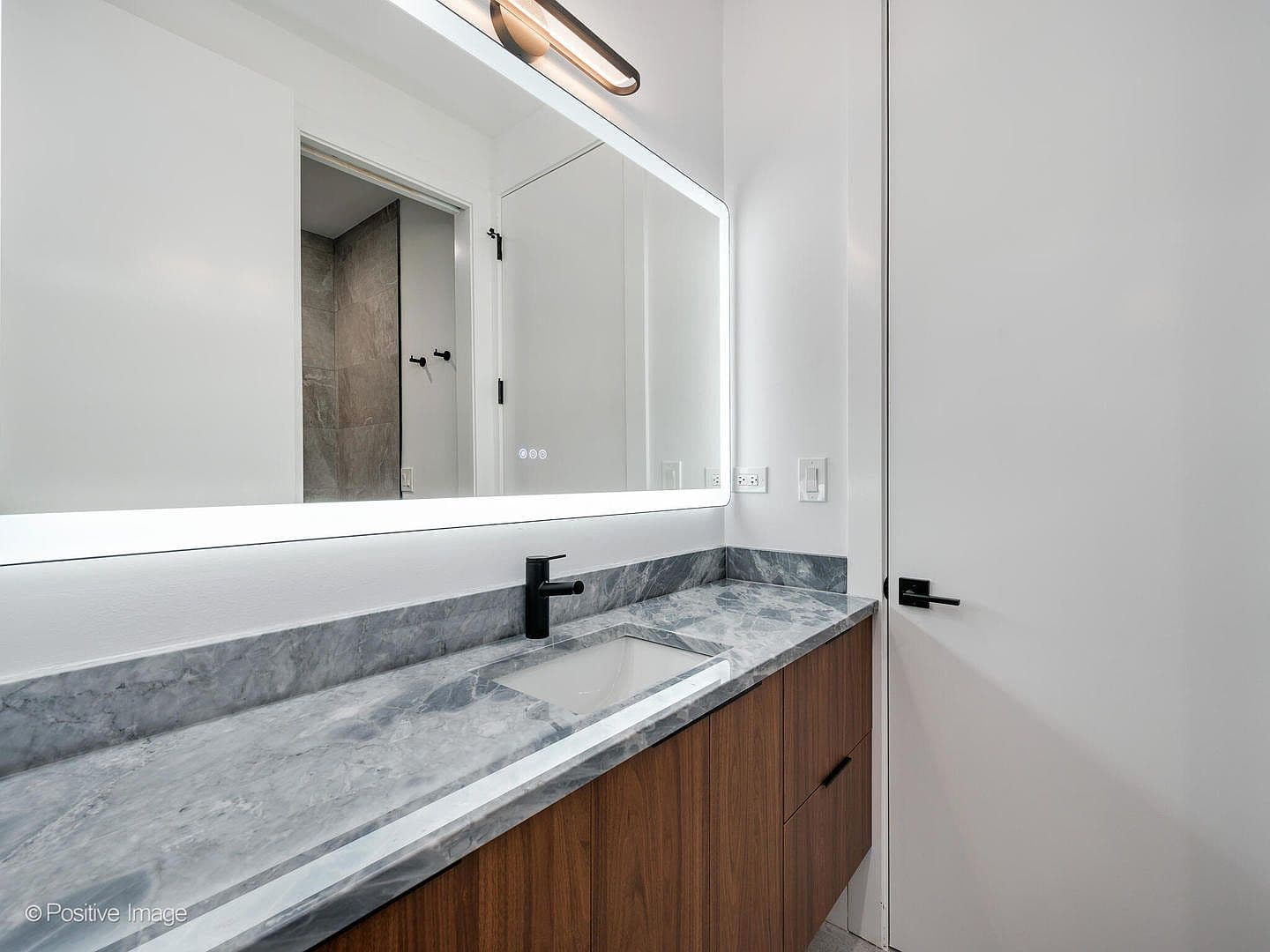 Guest bath with marble vanity and backlit mirror