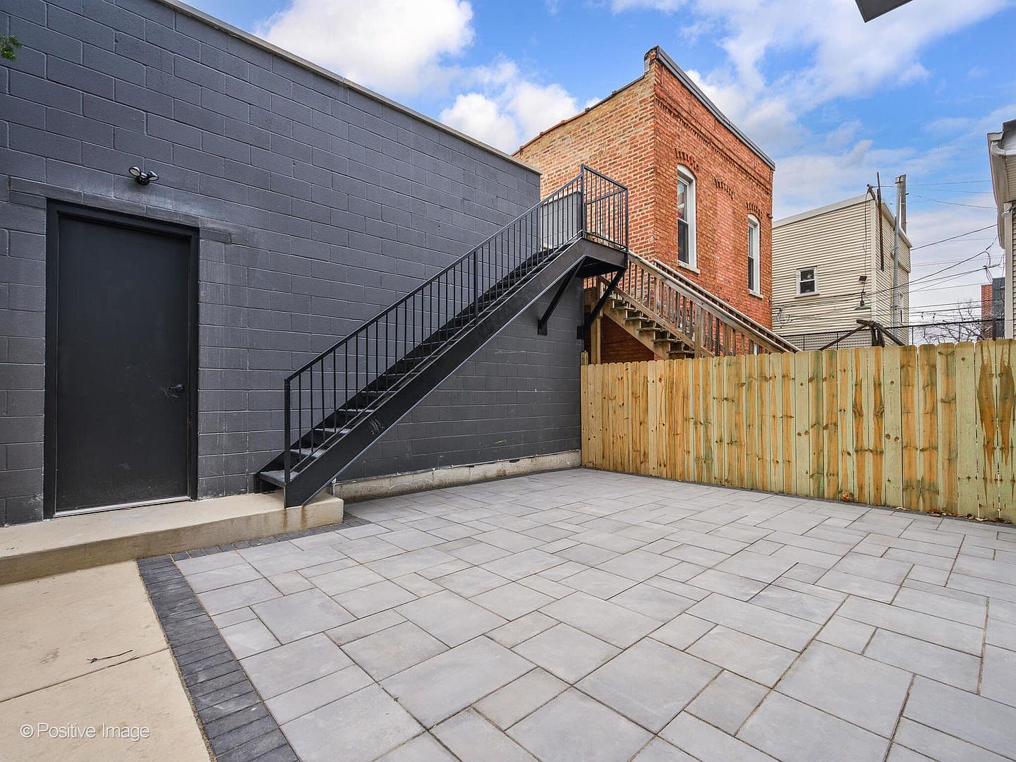Fenced backyard patio with stairs to upper deck