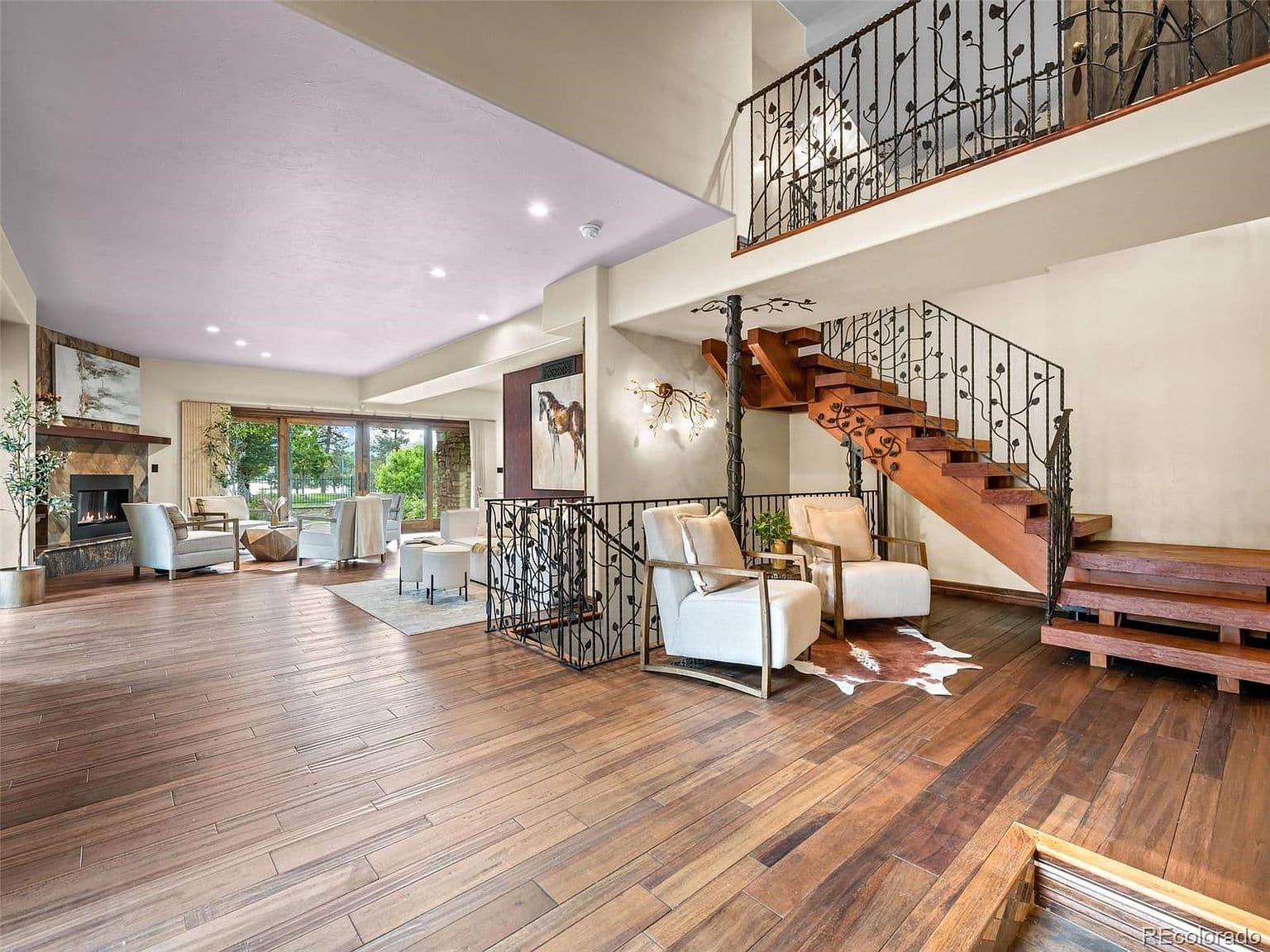Open living room pairs a fireplace with sculptural stairs