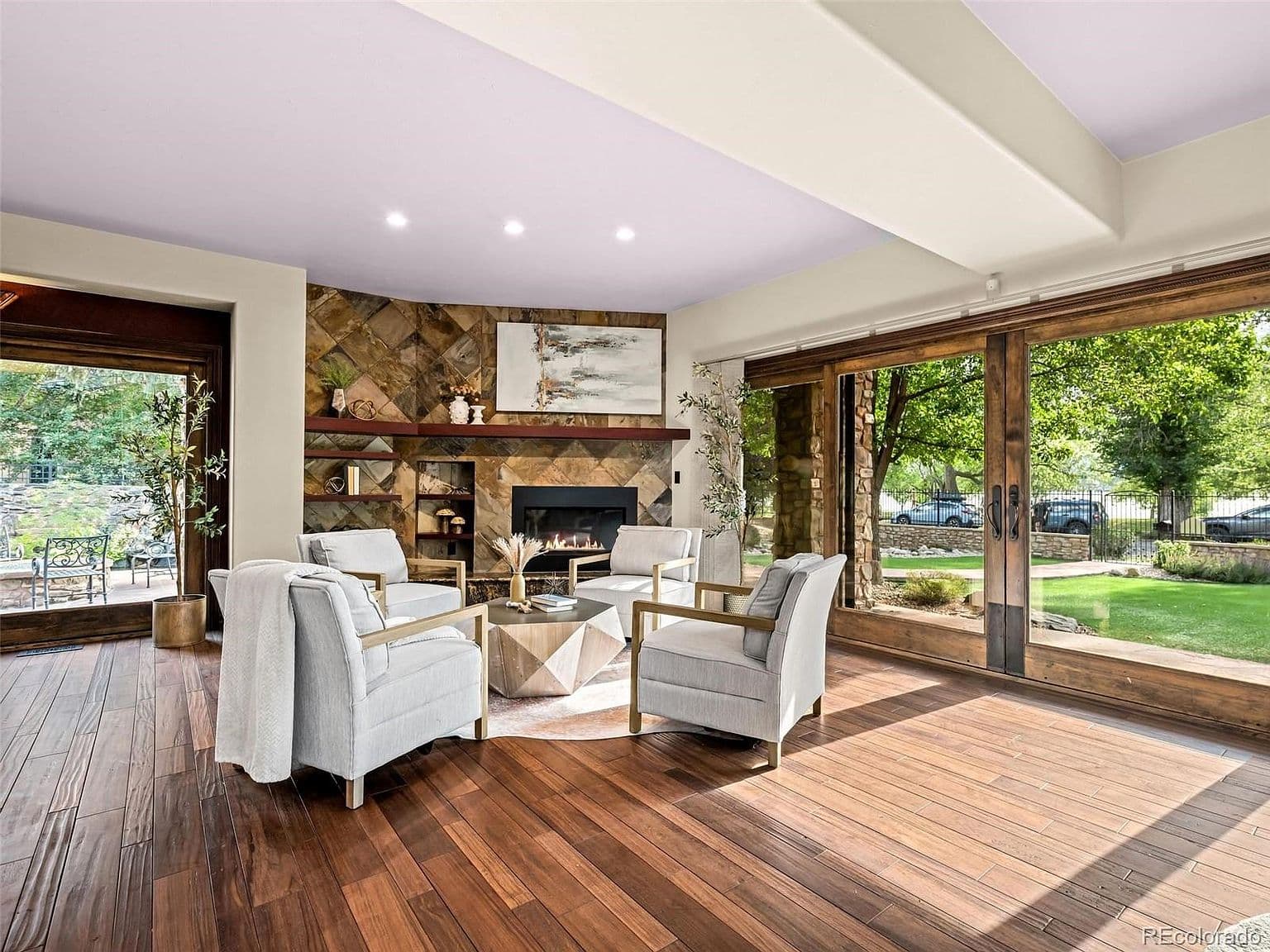 Sunlit living room with stone fireplace and garden views