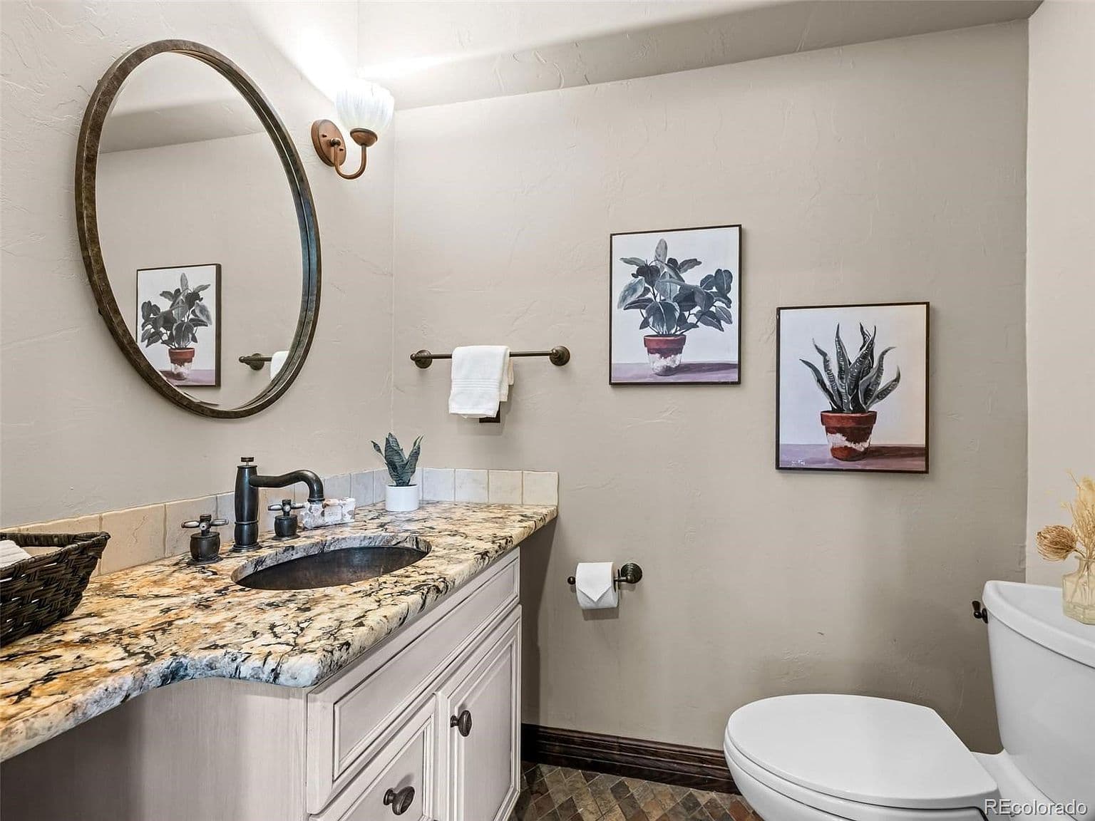 Stylish powder room features a richly patterned granite vanity