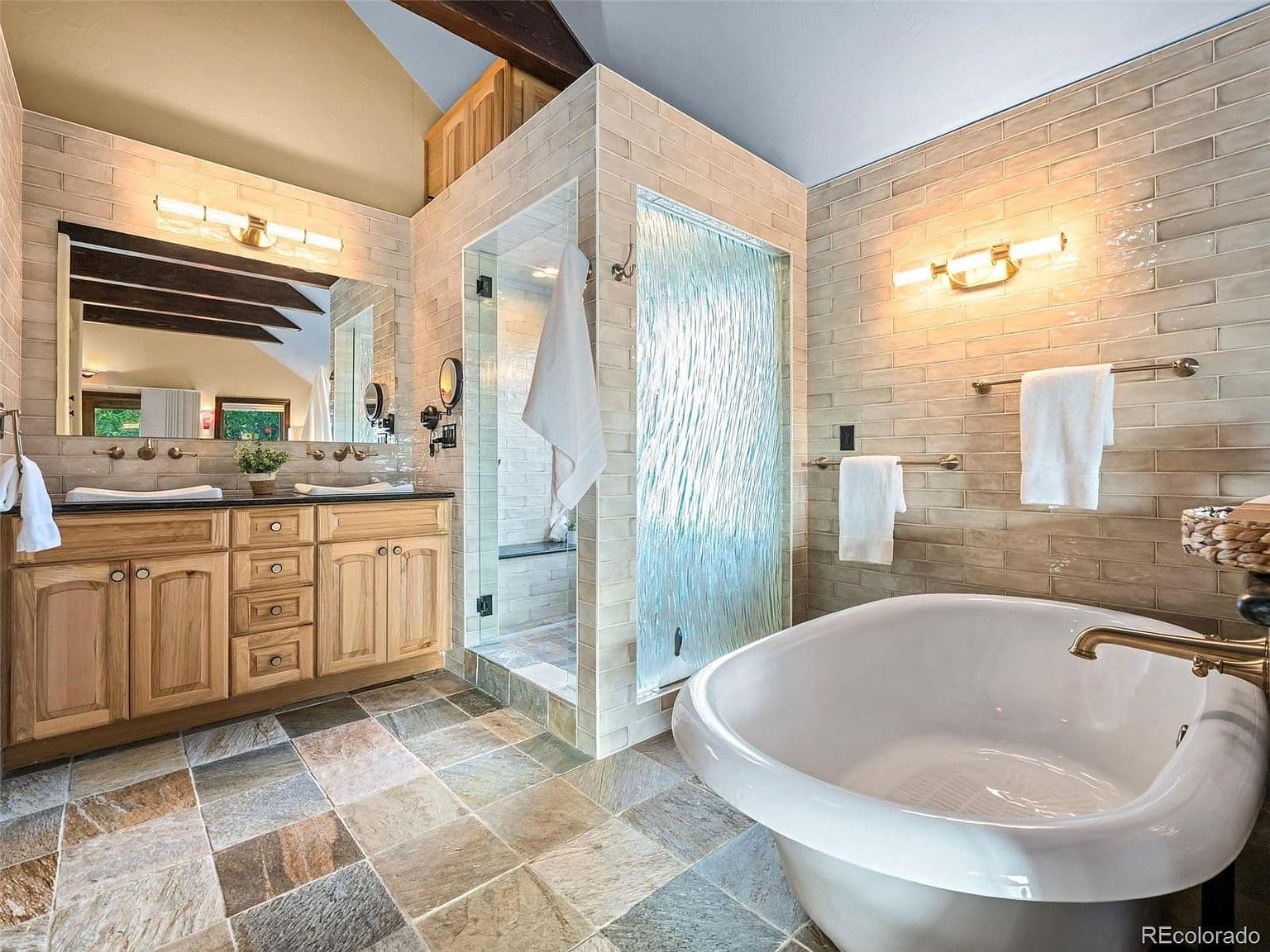 Freestanding soaking tub anchors the beautifully tiled bath.