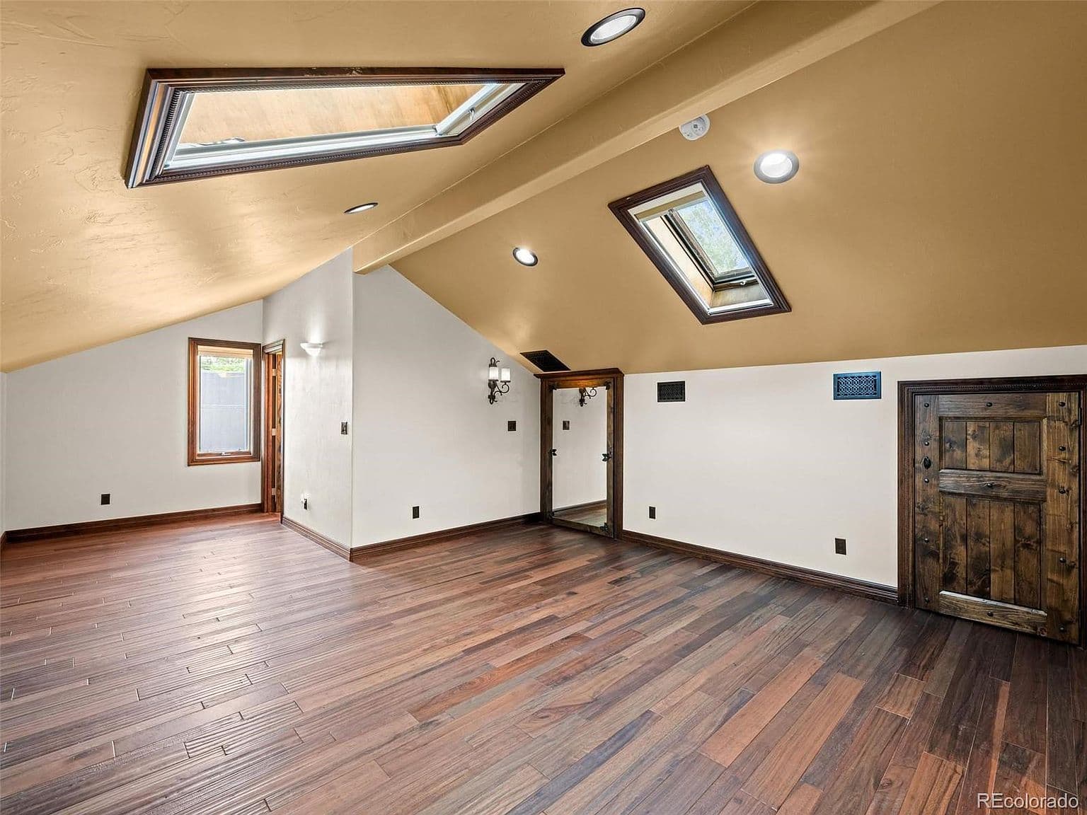 Skylights illuminate a versatile room with warm wood floors.