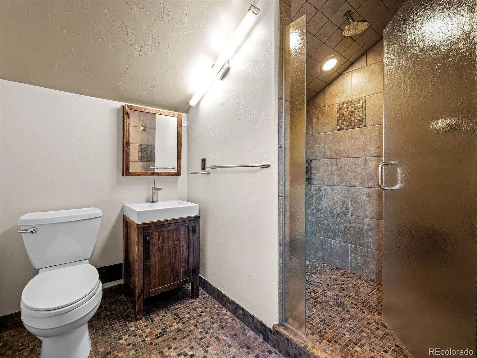 Tiled shower and rustic vanity complete this bathroom.