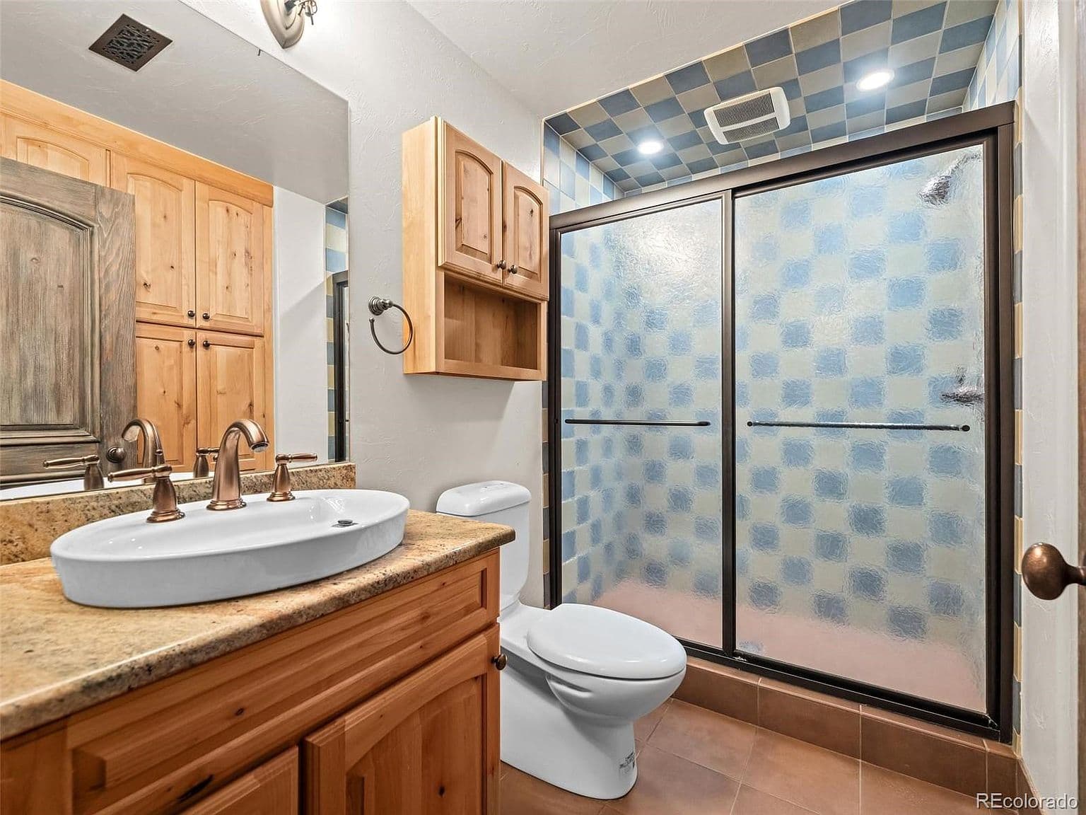 Bathroom features a vessel sink and glass-enclosed shower