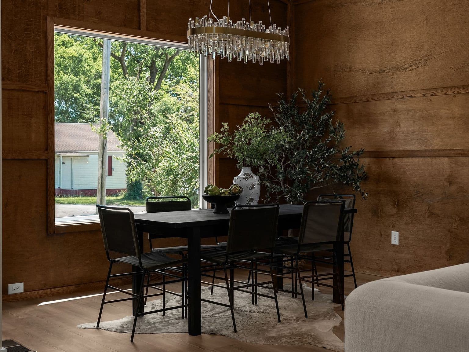 Dining nook framed by oversized window and statement chandelier.