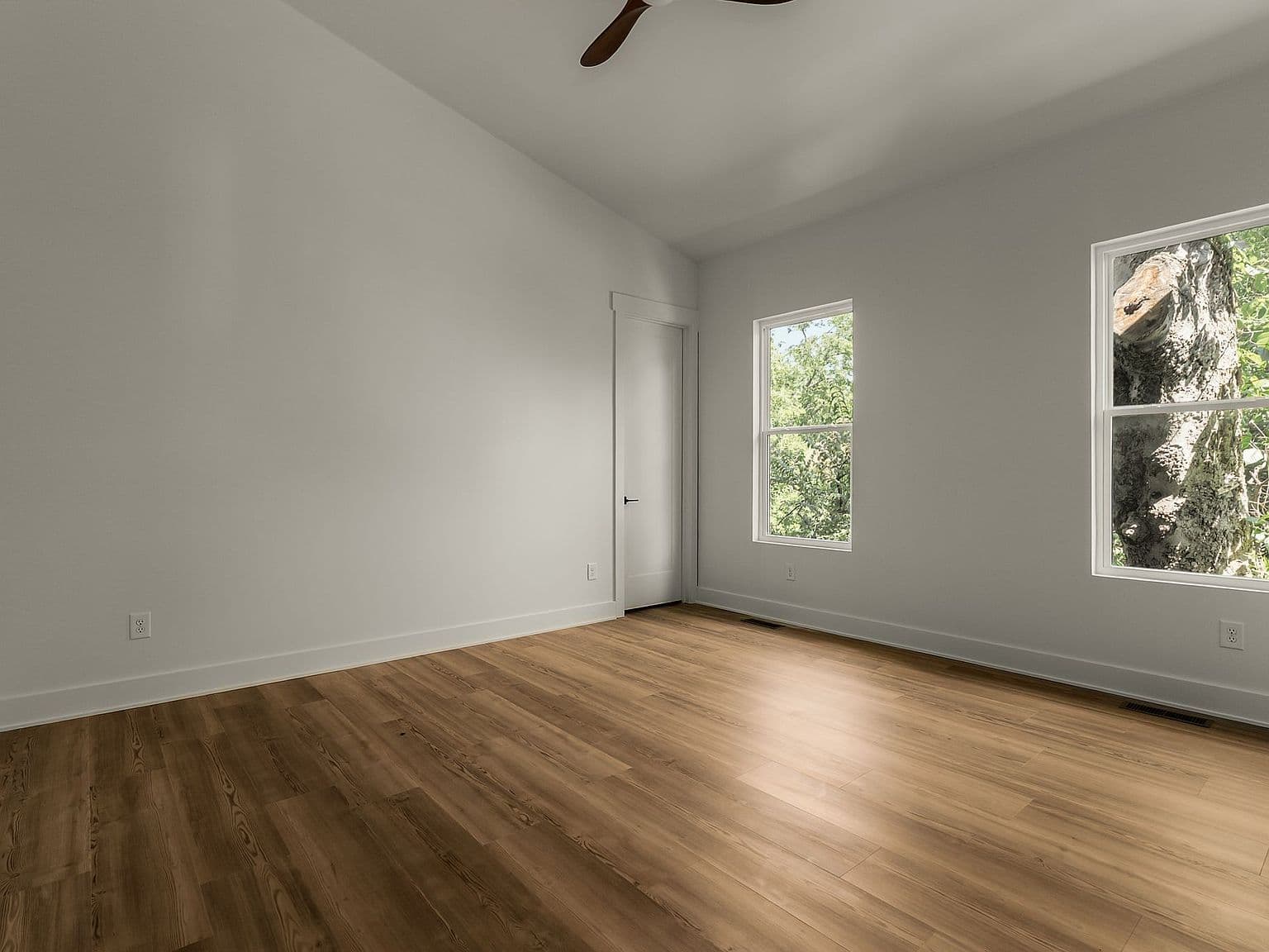 Sunlit bedroom with vaulted ceiling and wooded views.