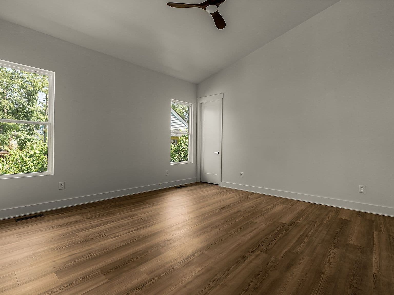 Bright guest bedroom with vaulted ceiling and leafy views.