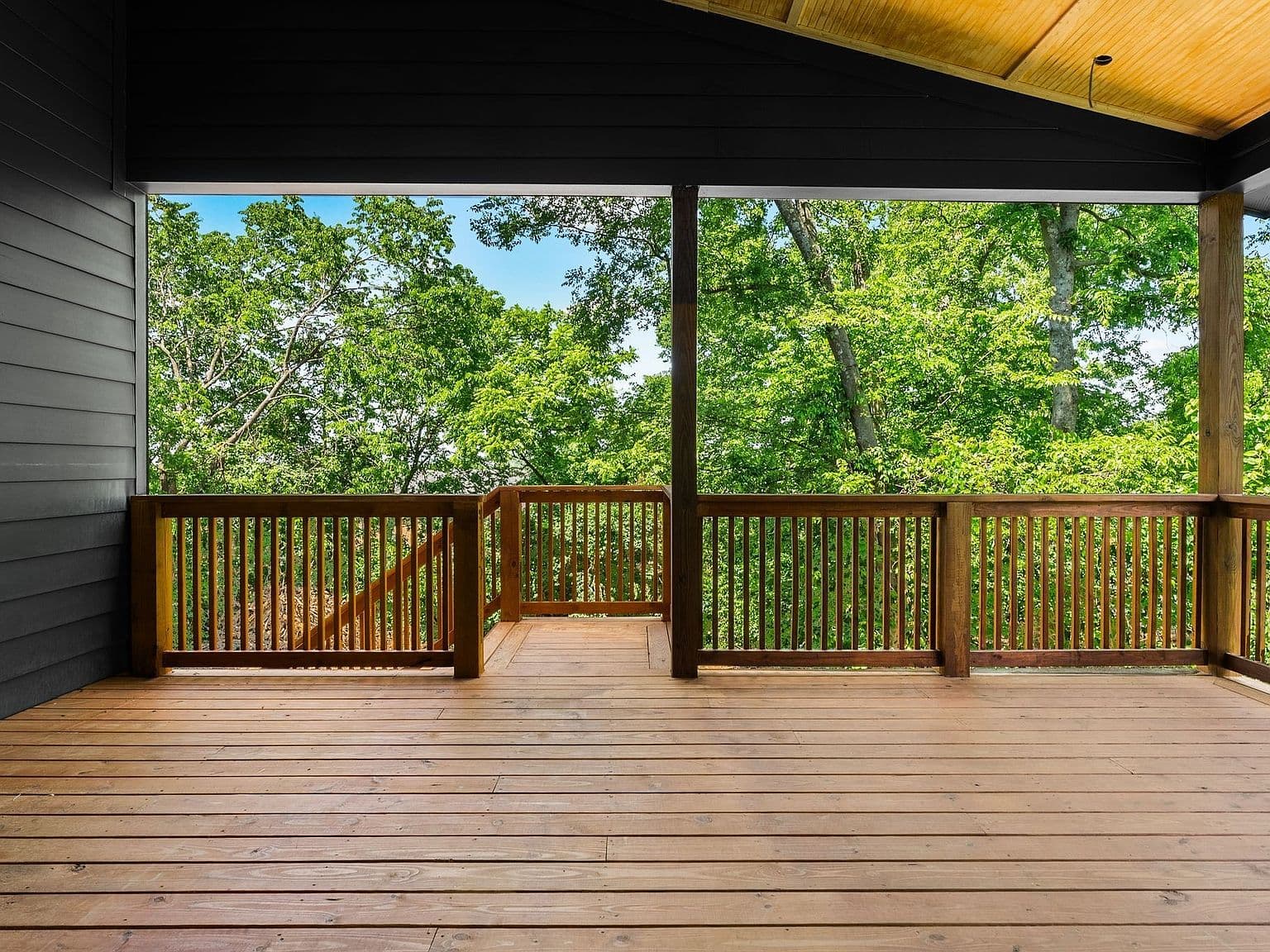 Covered deck retreat overlooking a private wooded backdrop.