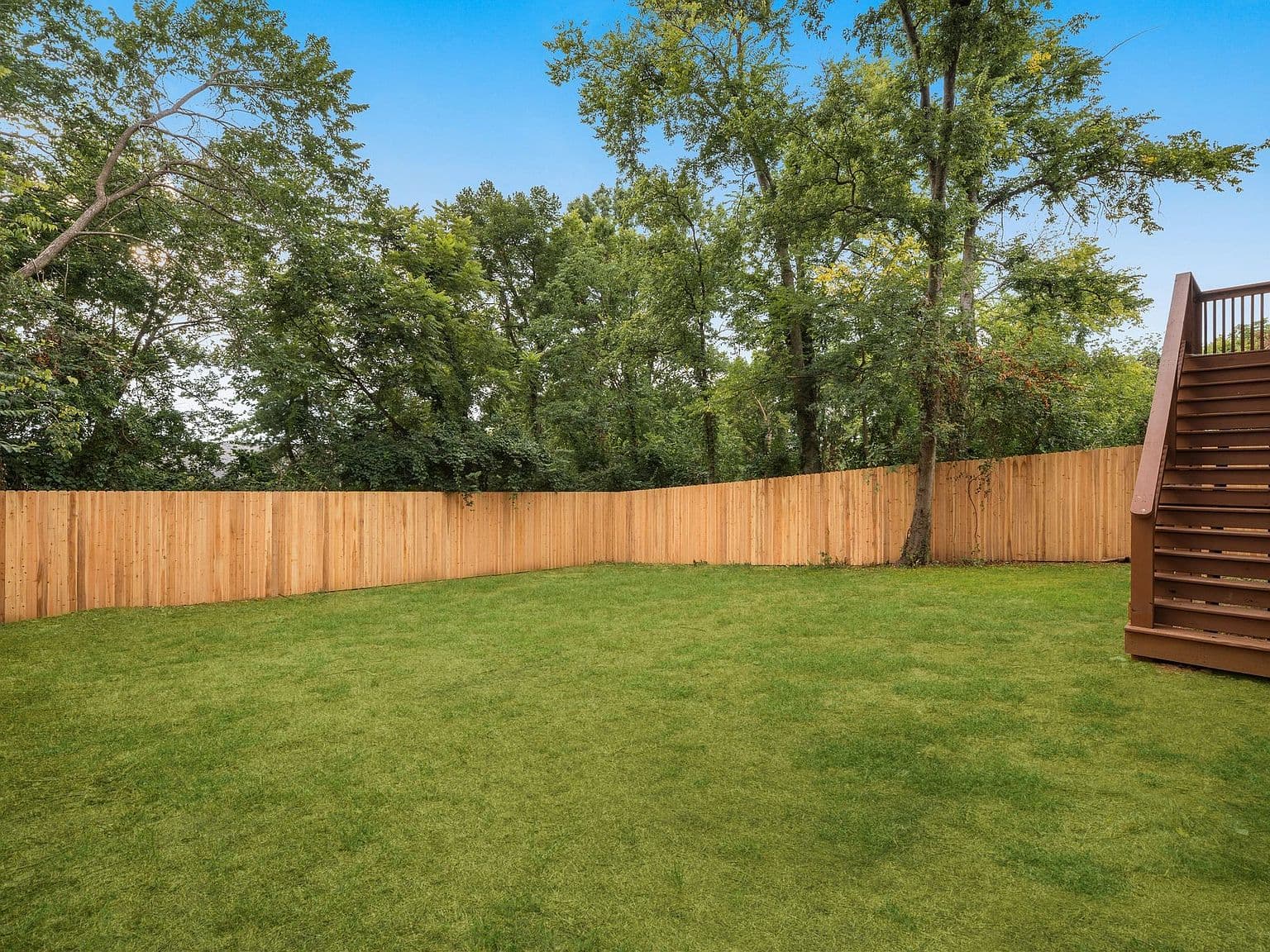 Fenced backyard oasis backing to peaceful mature trees.