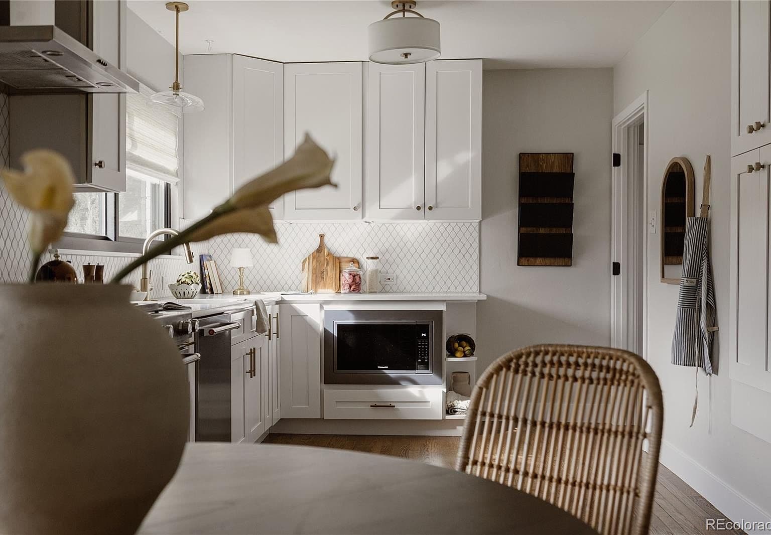 Sunlit kitchen pairs white cabinetry with patterned tile backsplash.