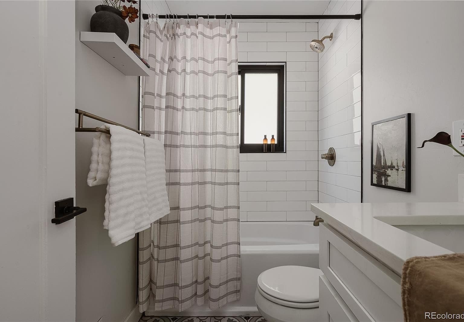 Bright full bathroom pairs subway tile with a sleek vanity.