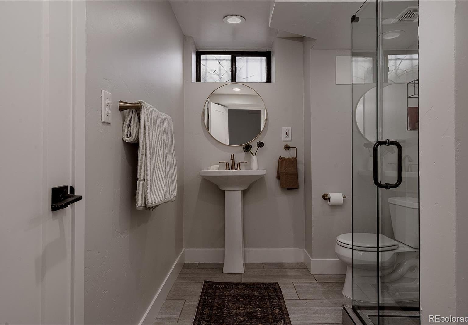 Stylish bathroom features a pedestal sink and glass shower.