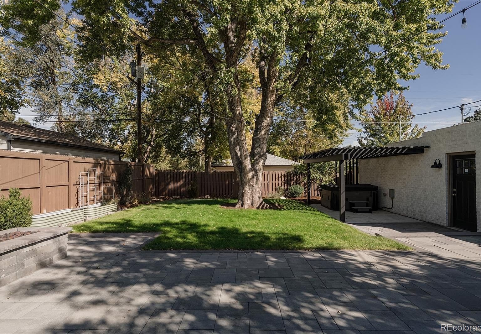 Tree-shaded backyard pairs green lawn with generous patio space.