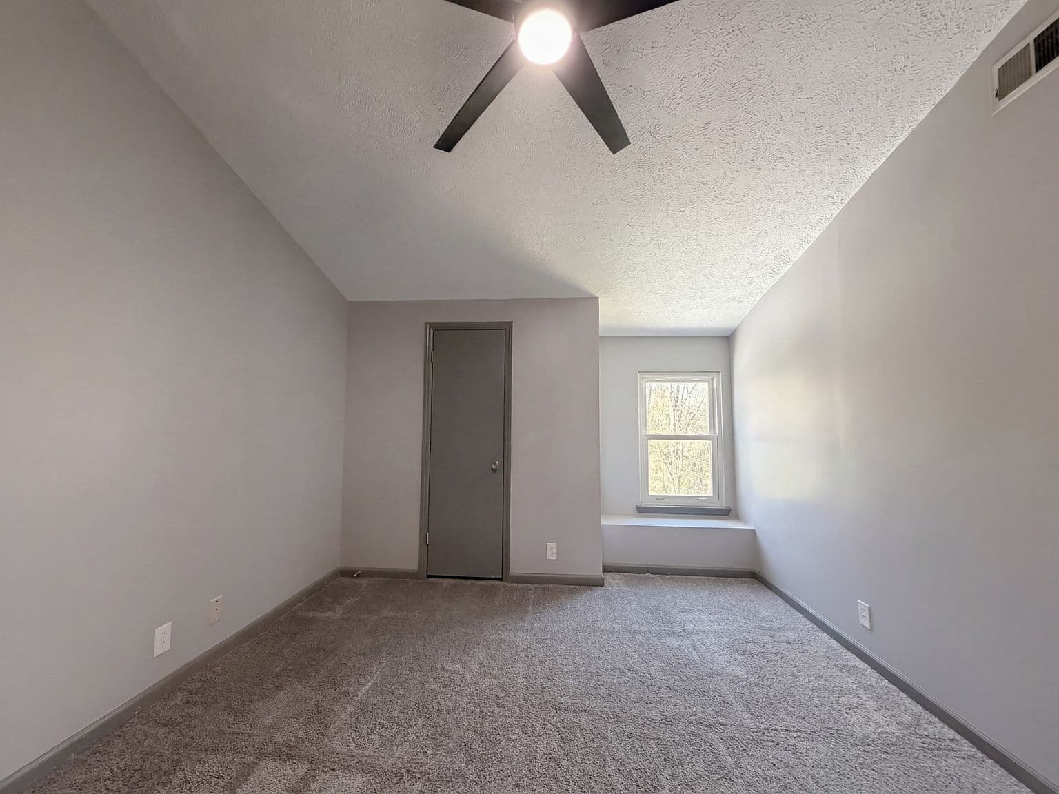 Upstairs bedroom with vaulted ceiling and plush carpeting.