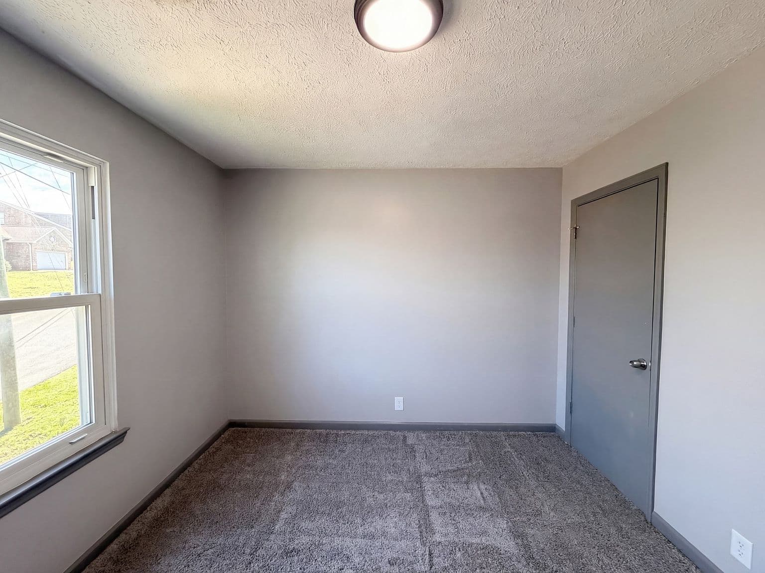 Sunlit upstairs bedroom with plush carpet and neutral tones.