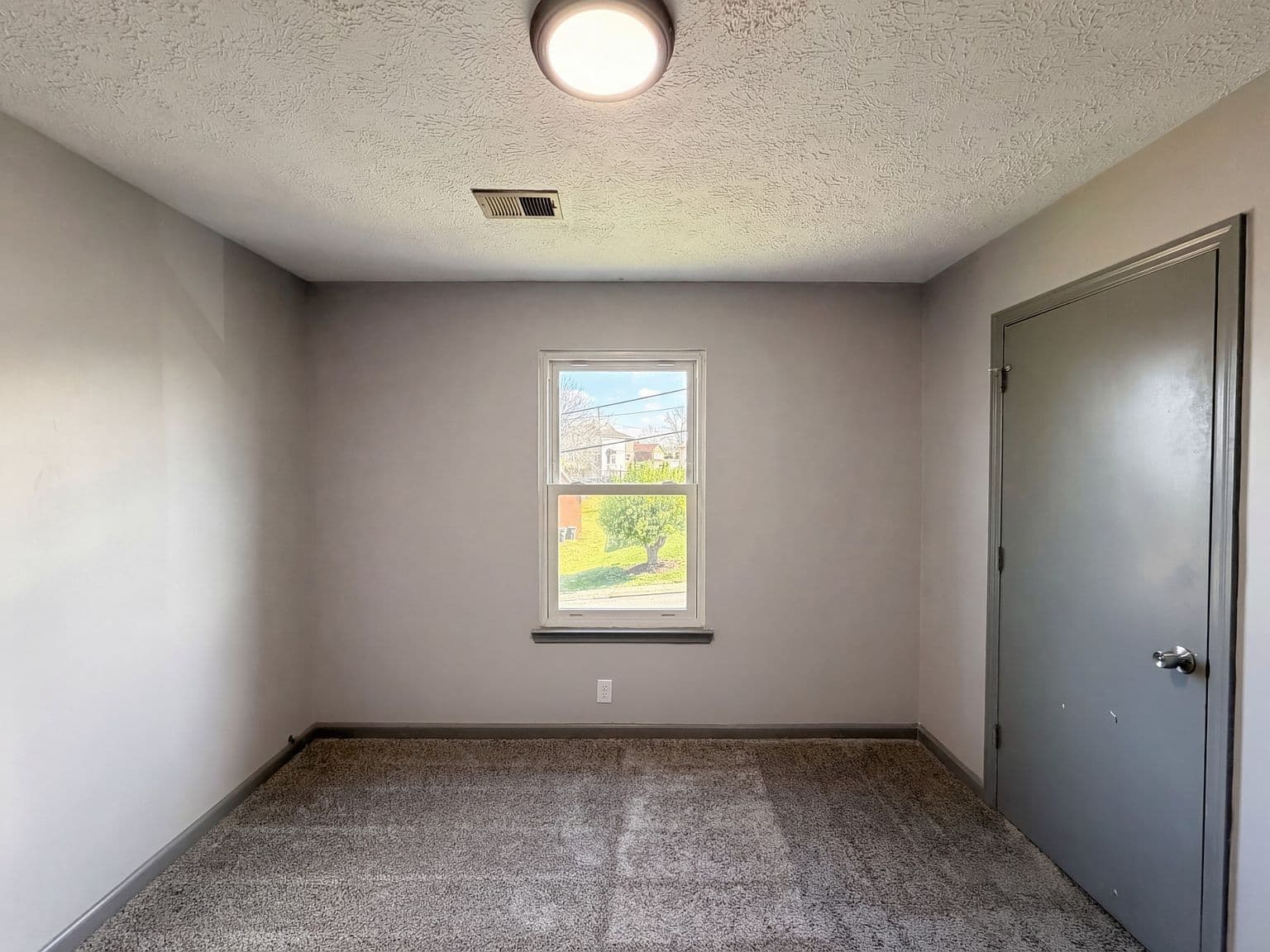 Cozy upstairs bedroom with bright window and soft carpet.