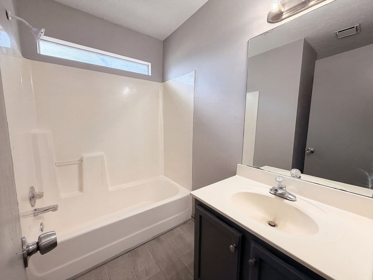 Fresh full bath with tub-shower combo and vinyl flooring.