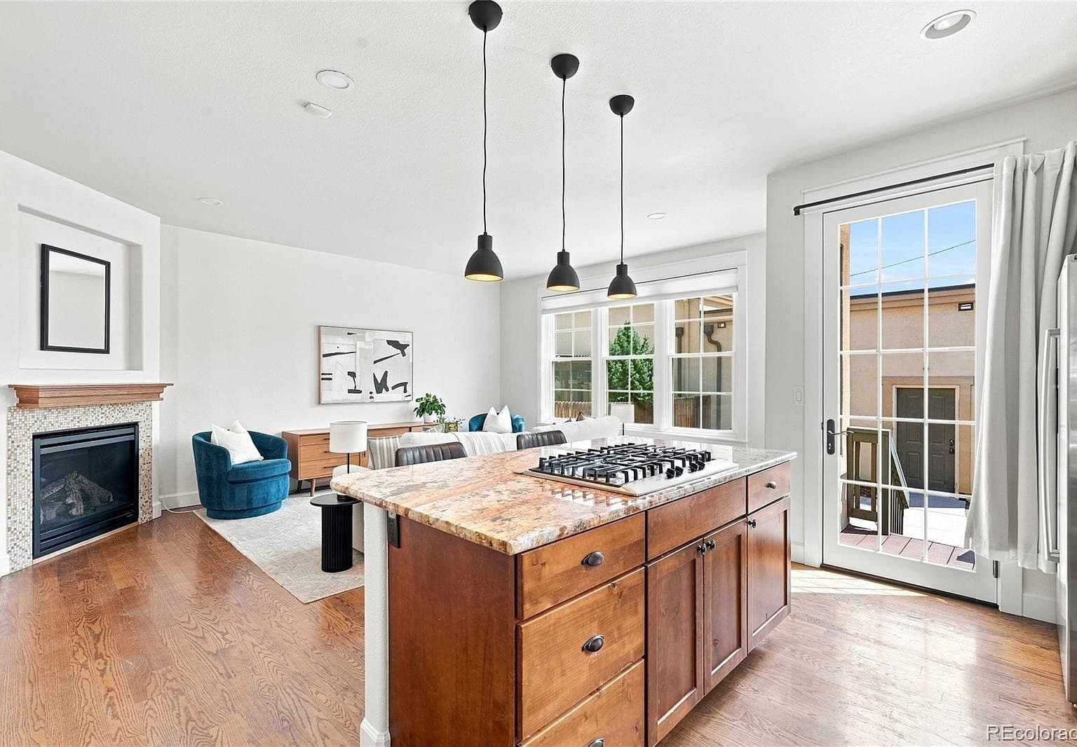 Open-concept living with fireplace and sunlit deck access.
