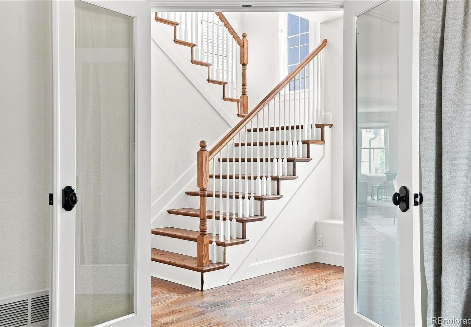 Elegant staircase framed by glass French doors.