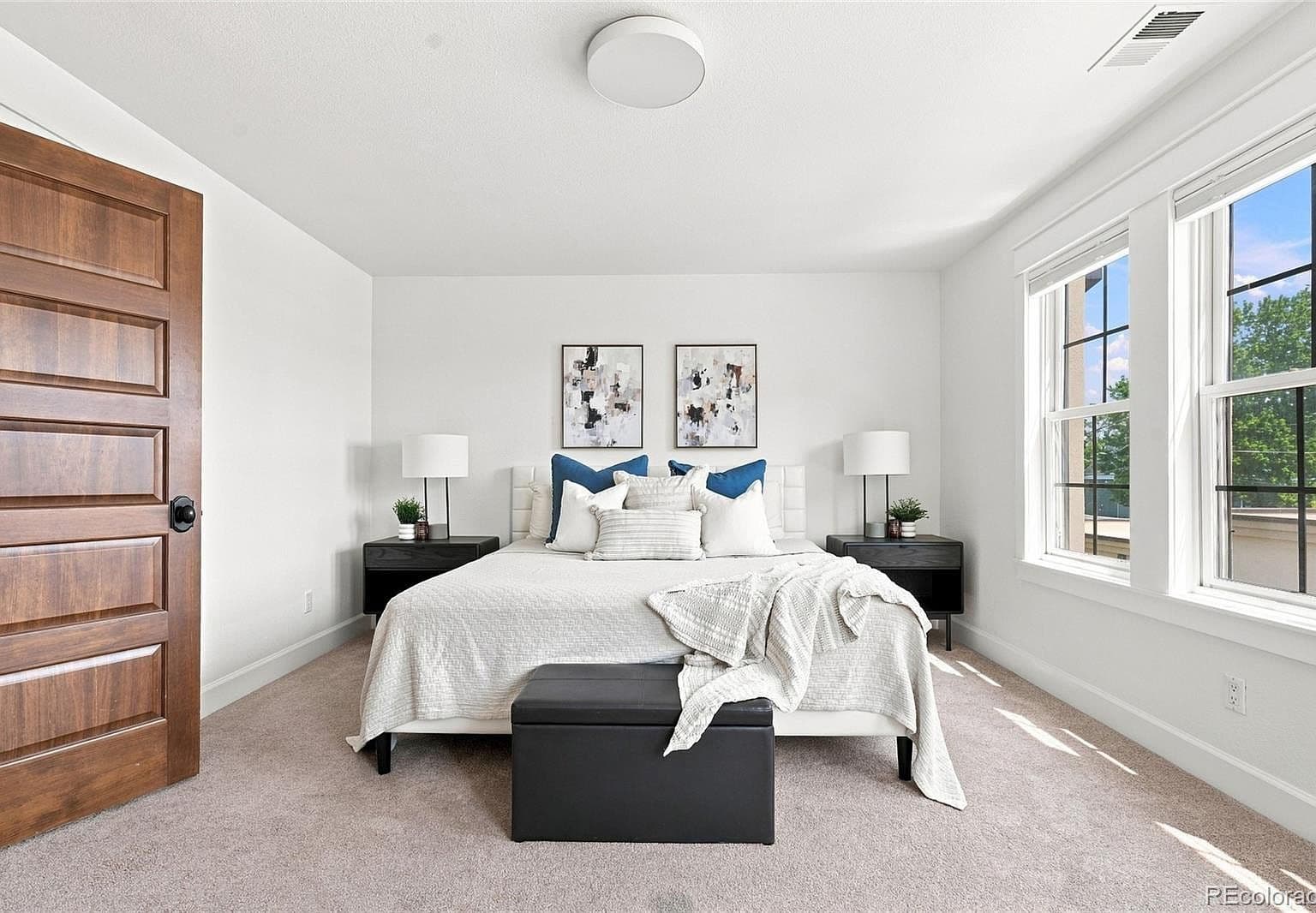 Spacious bedroom with large windows and plush carpeting.