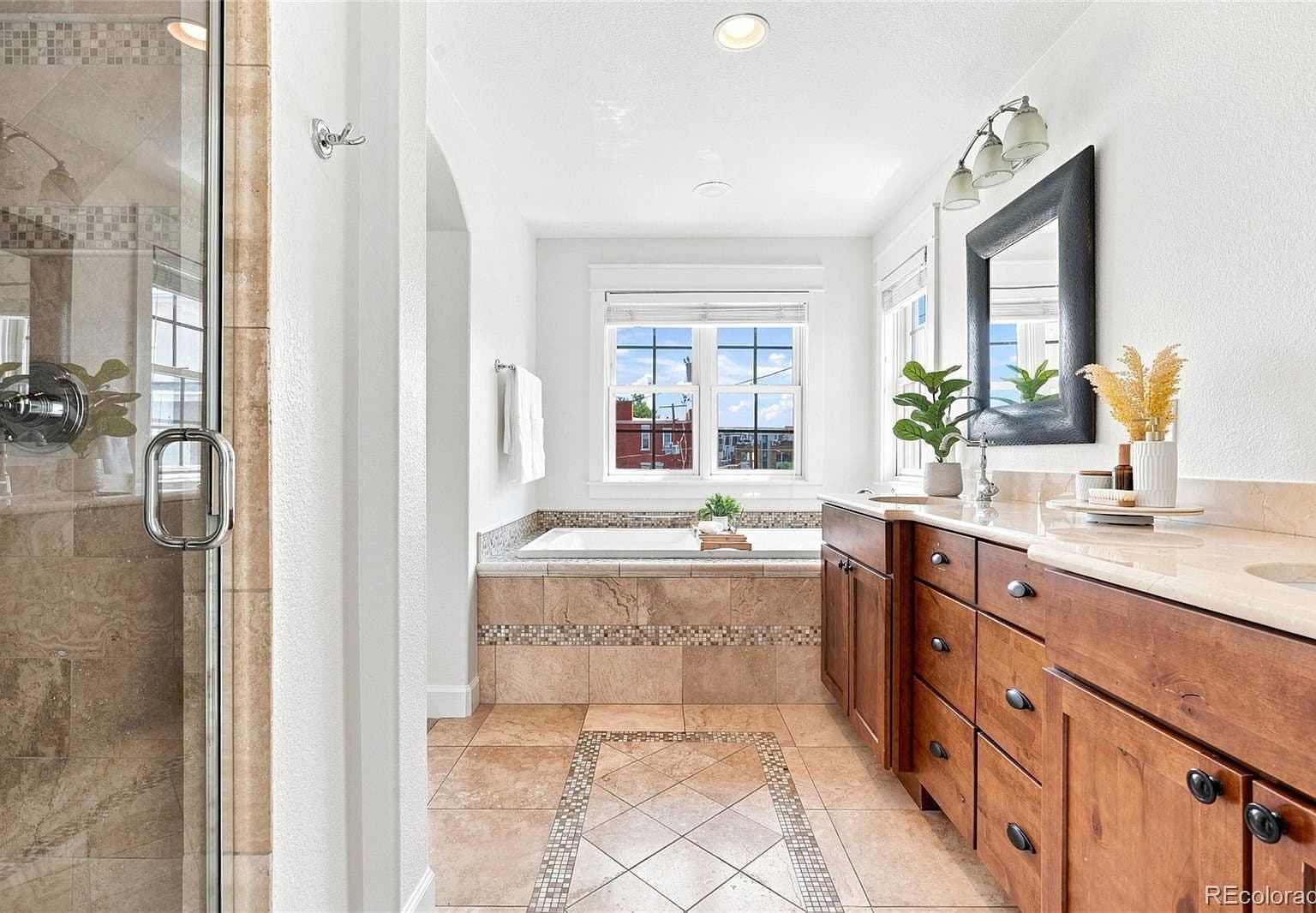 Bright primary bath with tiled shower and sunlit tub.