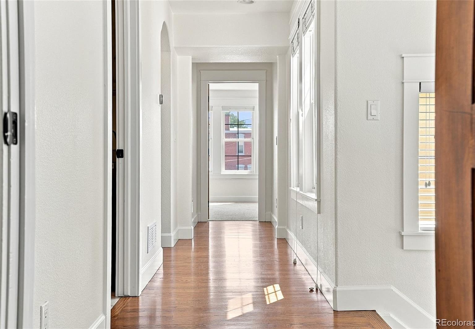 Light-filled hallway with gleaming hardwood floors throughout.