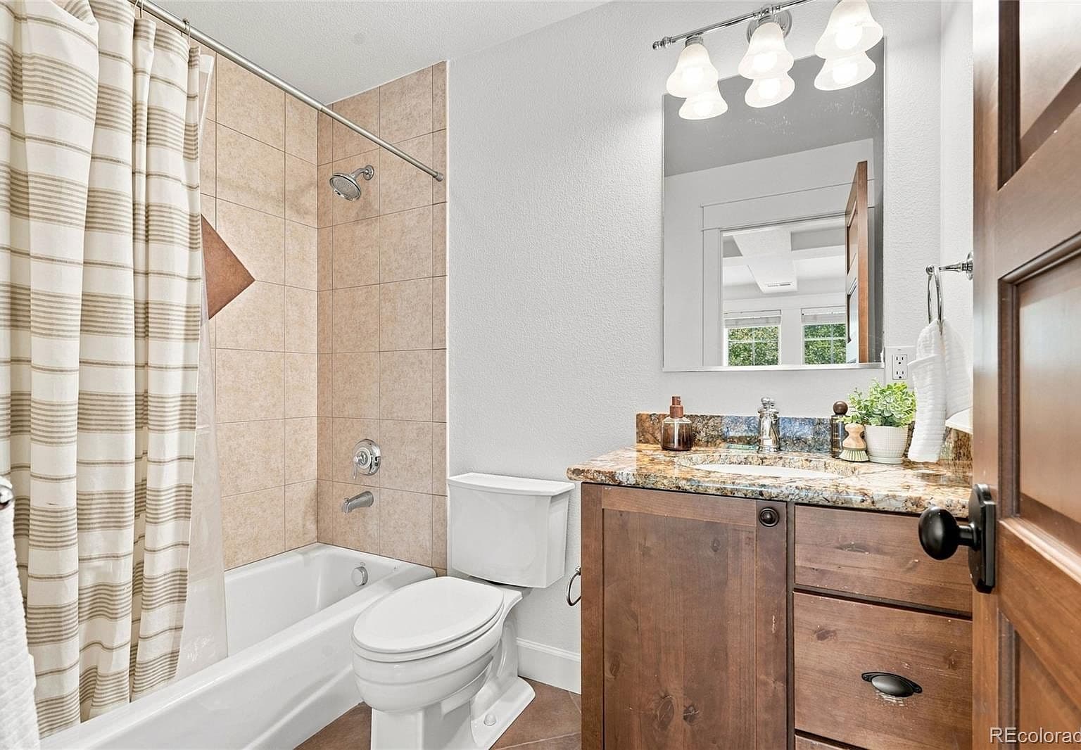 Chic full bath with granite vanity and tiled shower.