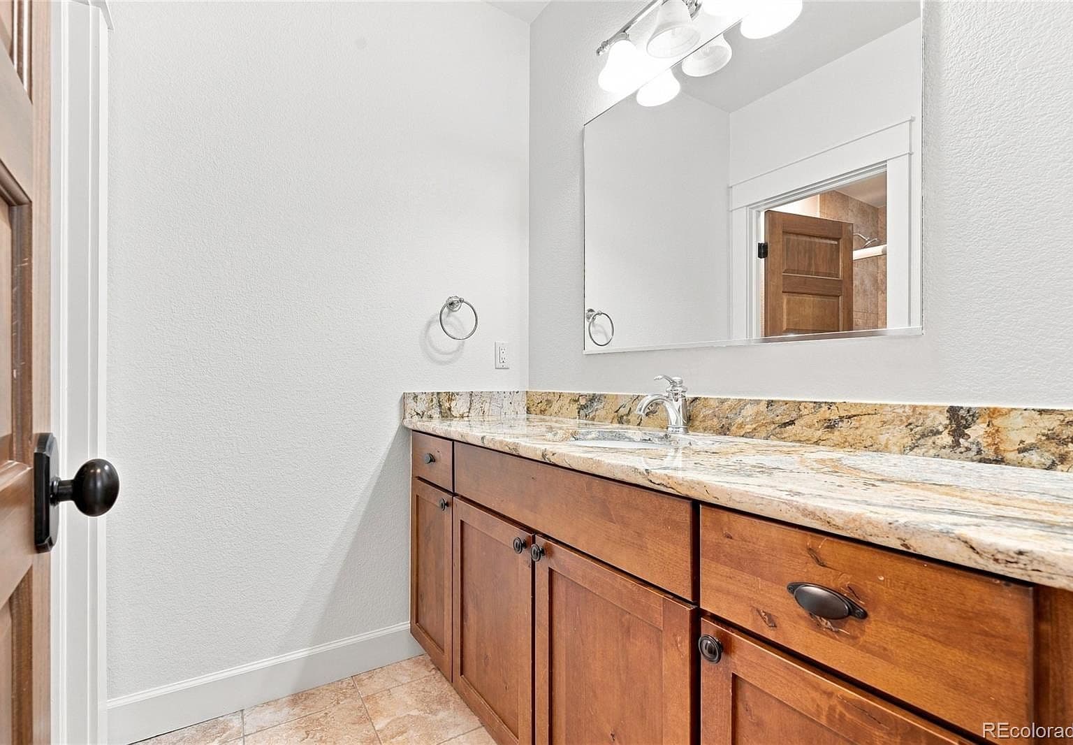Granite-topped vanity brings warmth to bright bath.
