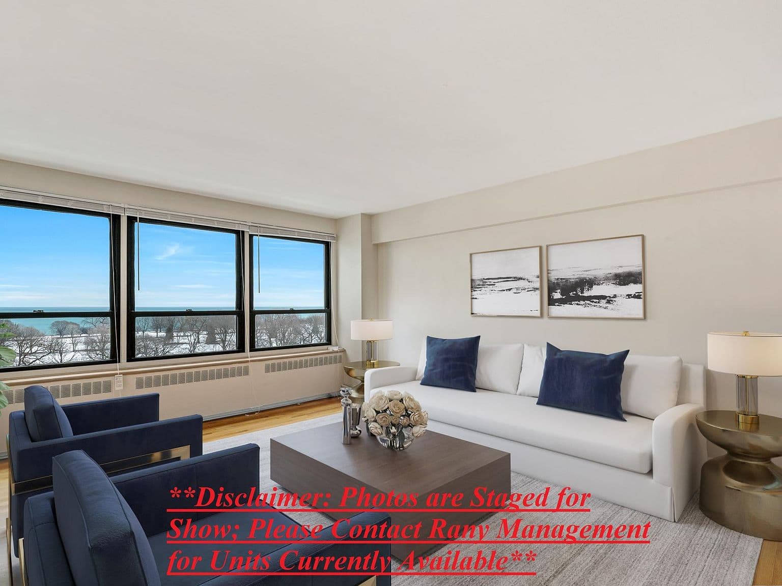 Staged living room showcases wide windows and a lake outlook.