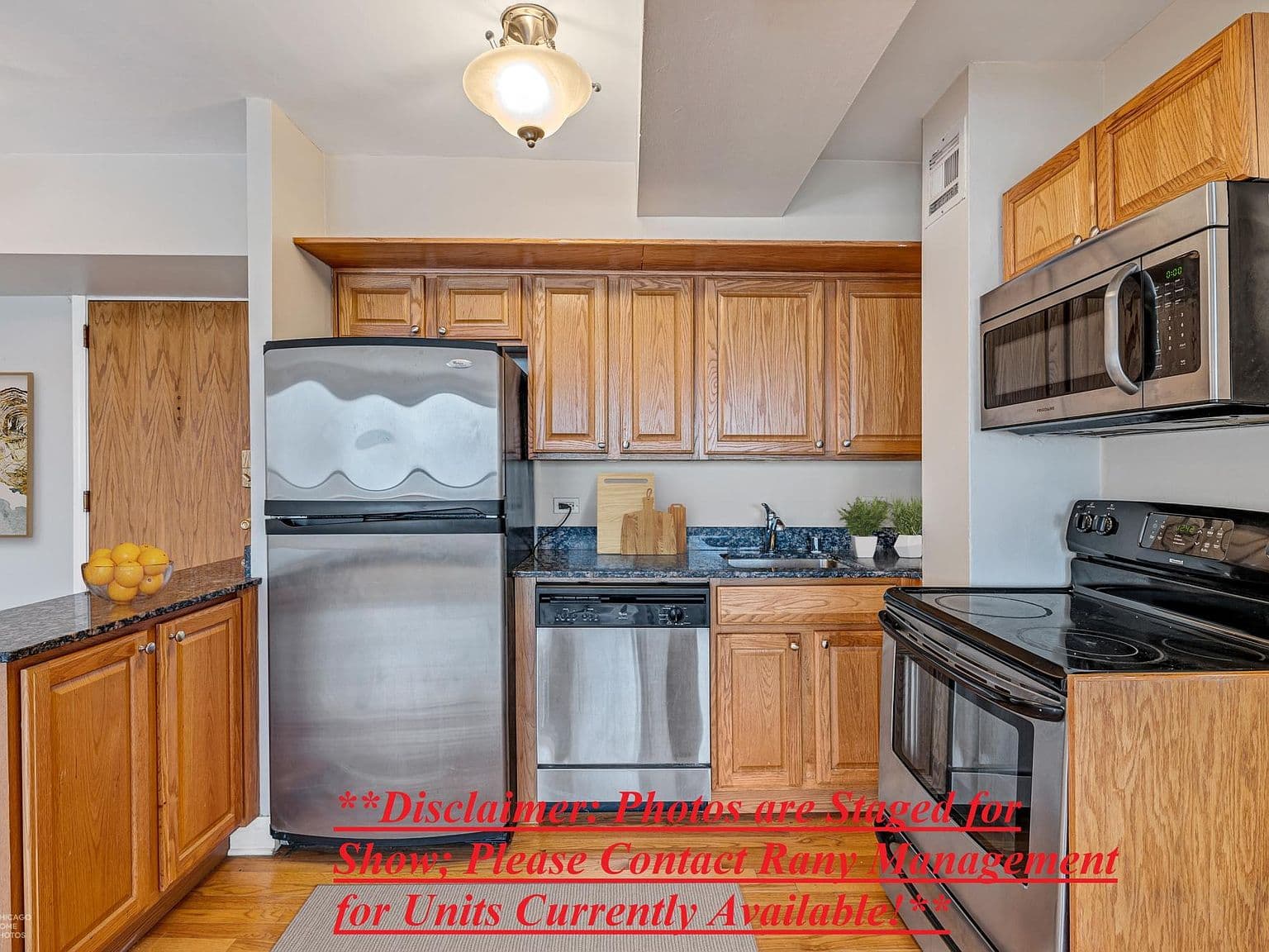 Staged kitchen features wood cabinetry and stainless steel appliances.