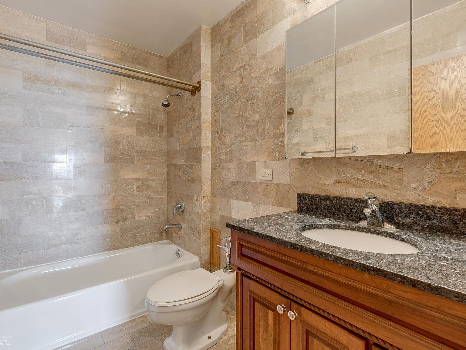 Second full bathroom features stone-look tile and a bathtub.