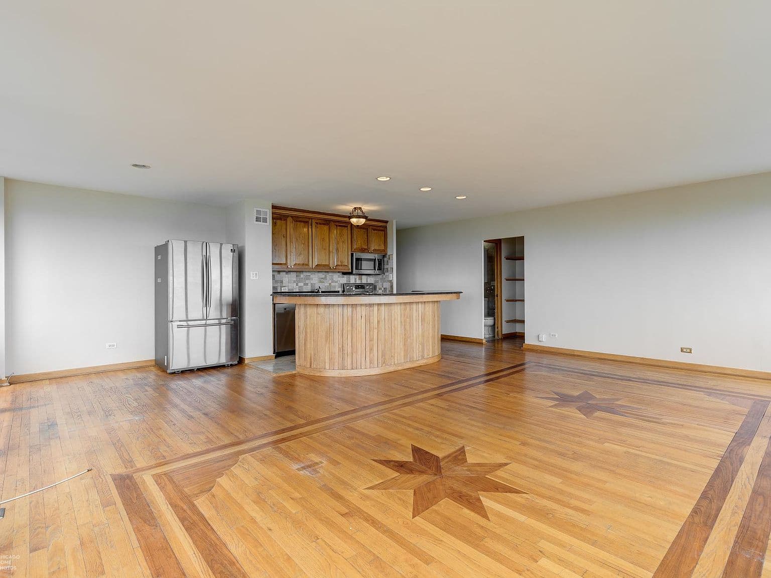 Open living area showcases hardwood floors and a distinctive inlay.