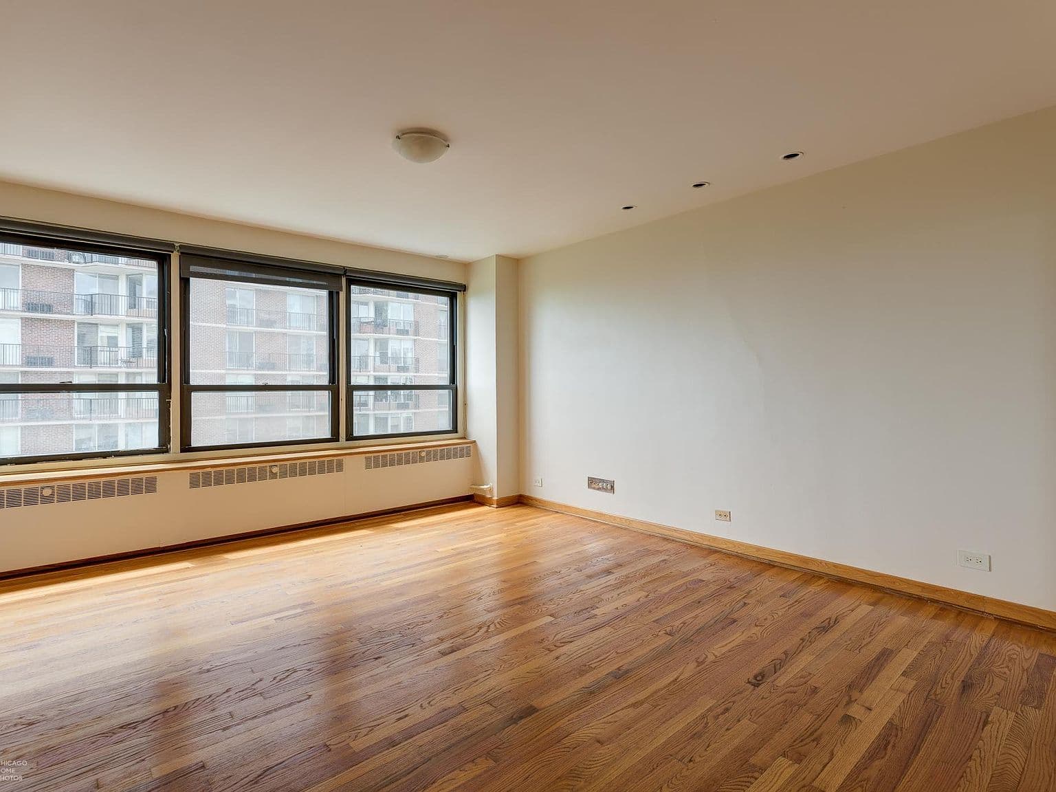 Bright bedroom offers hardwood floors and a wall of windows.