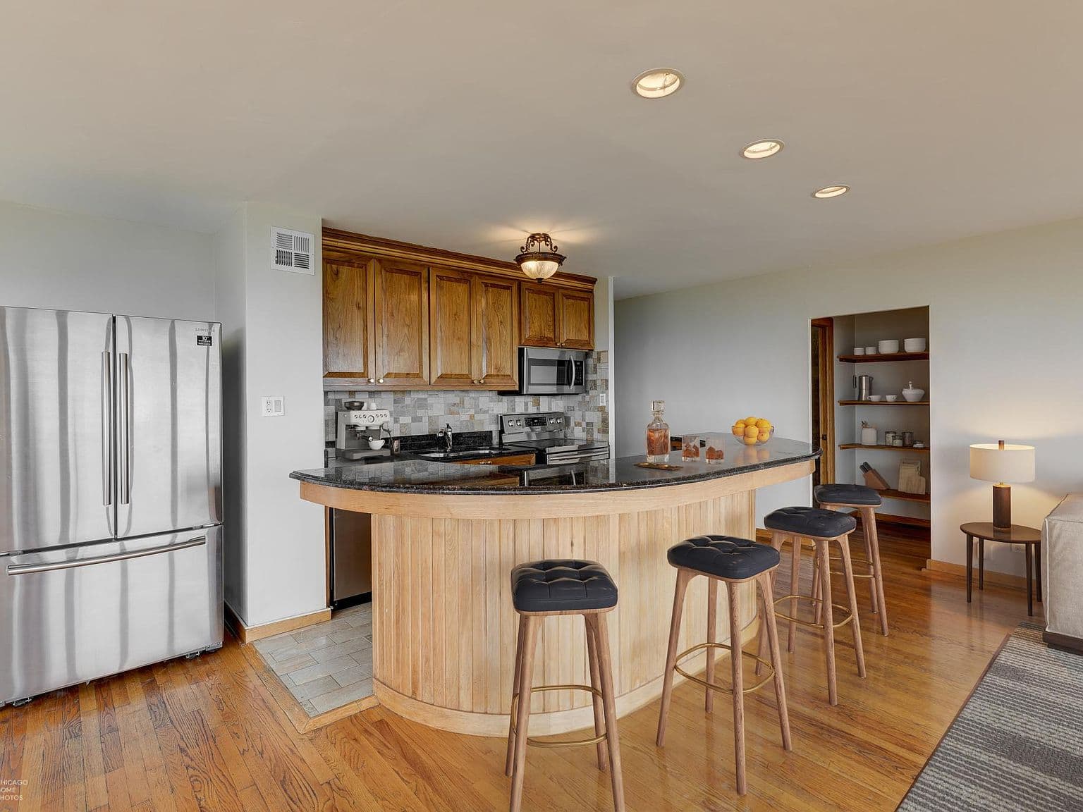 Curved breakfast bar anchors the kitchen with stainless appliances.