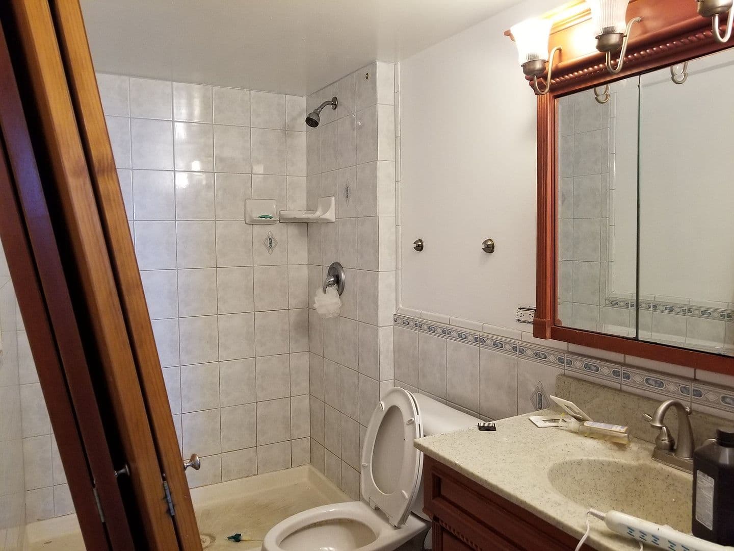 Tiled bathroom features a shower and wood-framed vanity.