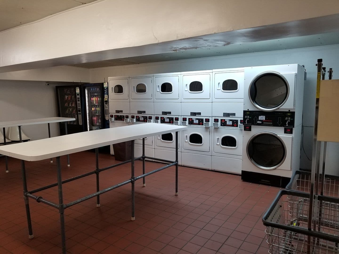 Basement laundry room offers multiple machines and folding tables.