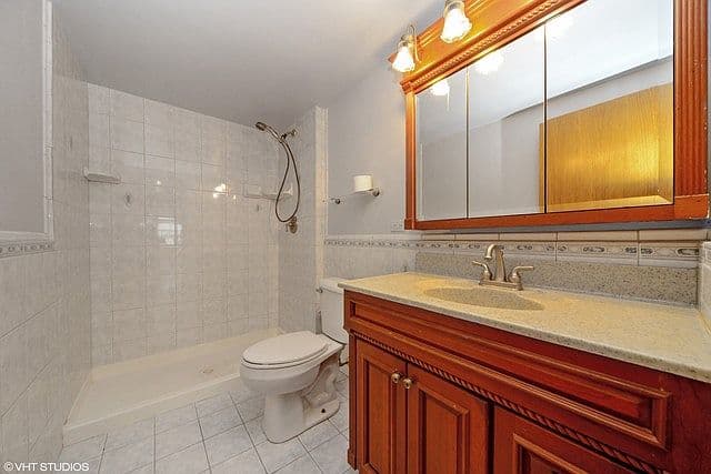 Tiled bathroom pairs a walk-in shower with wood vanity