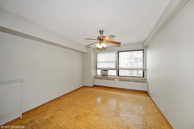 Airy bedroom features hardwood floors and a ceiling fan