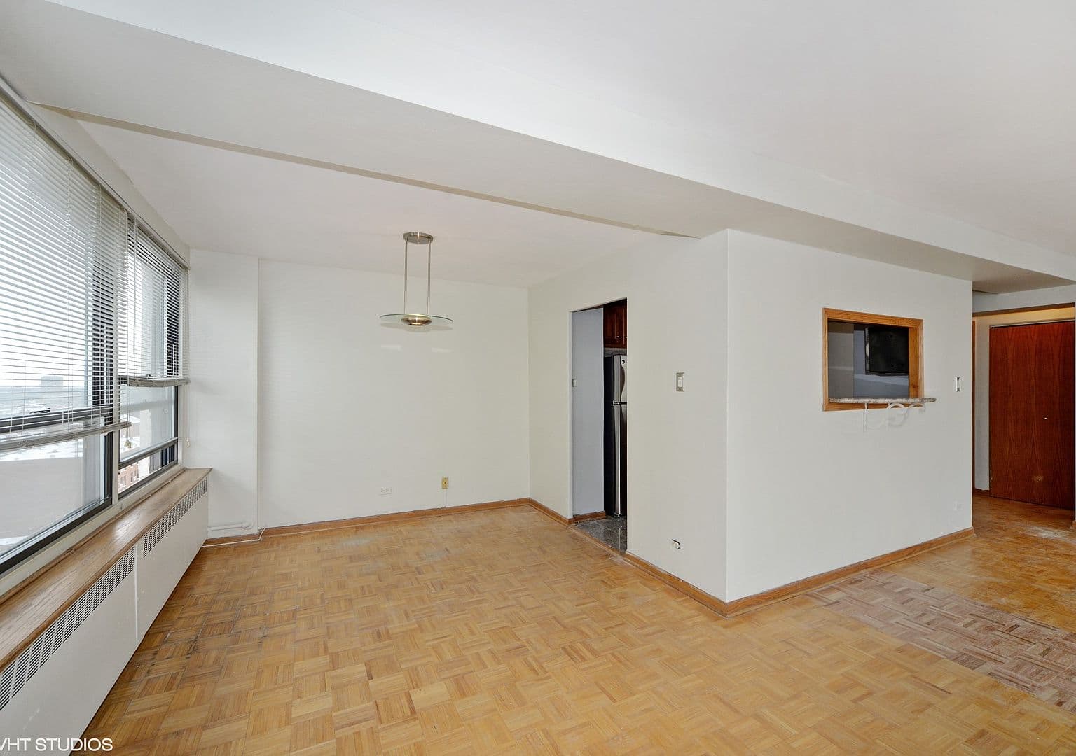 Sunlit dining area features parquet floors and kitchen access.