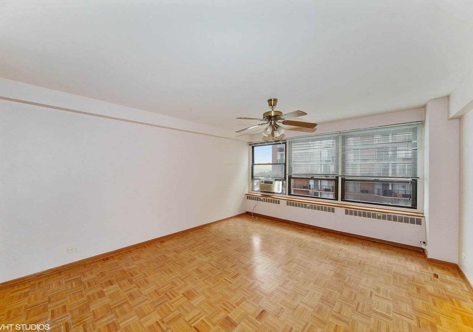 Spacious bedroom pairs parquet floors with wide windows.