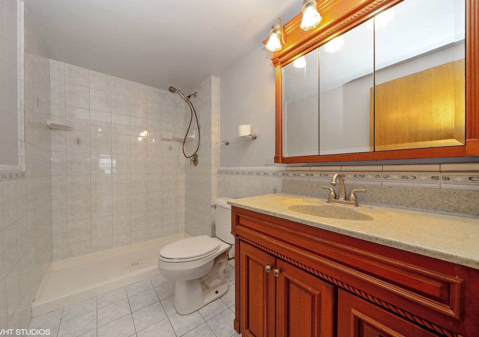 Full bathroom features a tiled shower and wood vanity.